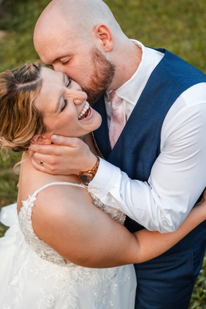 Groom kisses a laughing bride on the cheek.
