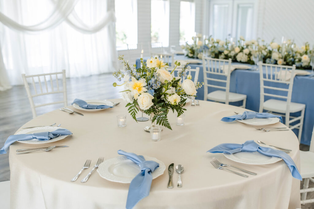 Table center pieces and plates set at indoor wedding reception.