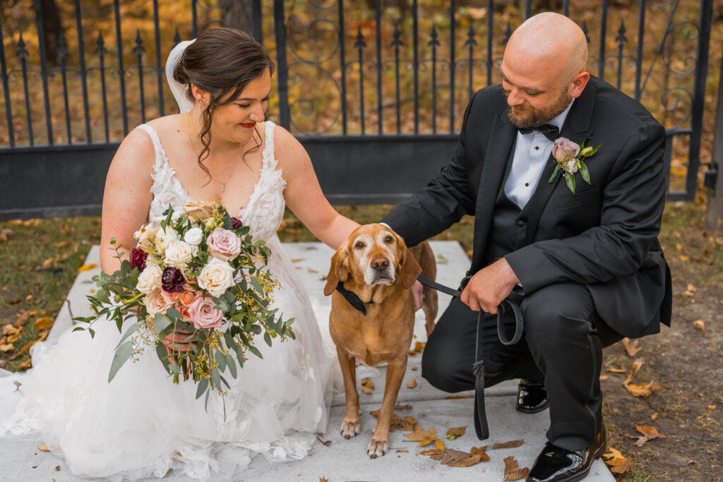 Bride and groom pet their dog at their wedding at The Bluffs at Conner Prairie wedding venue.