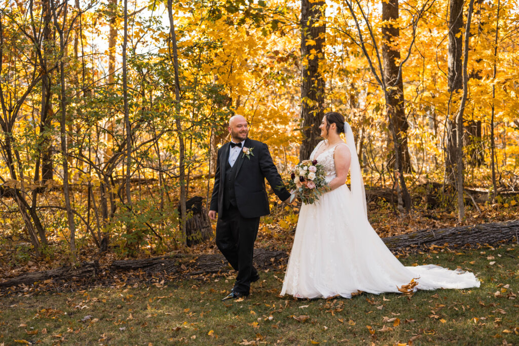 Bride and groom holding hands while walking through the forest.