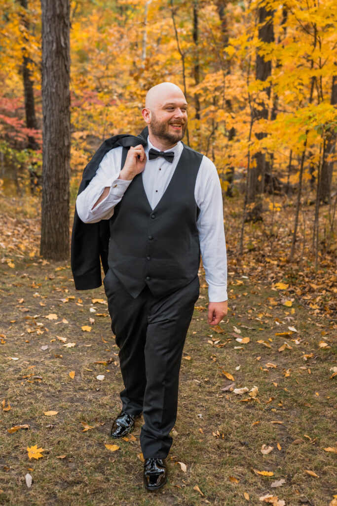 Groom laughing as he walks with his jacket over his shoulder.