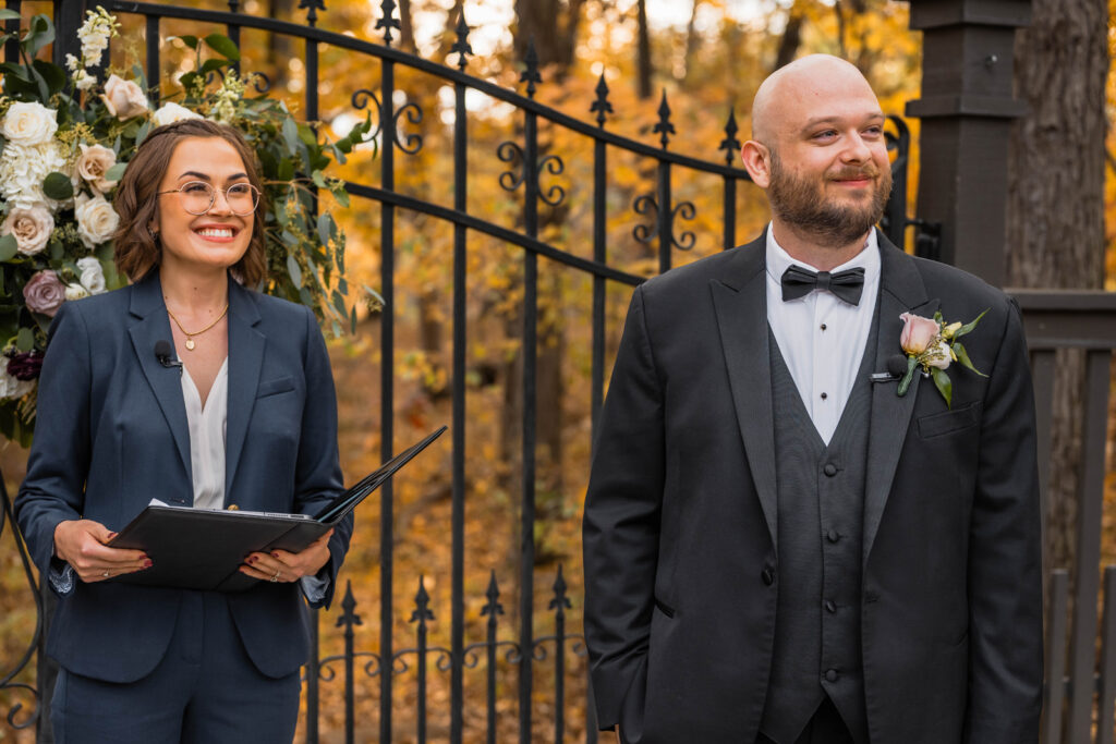 Groom smiles while bride walks down the aisle.