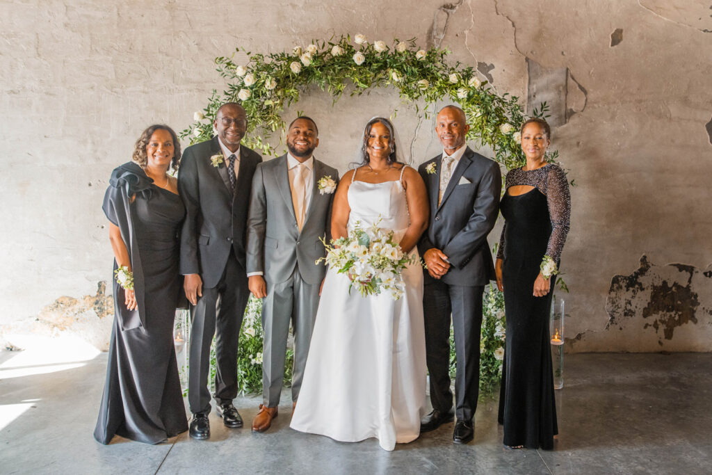 Bride and groom smiling with their parents.