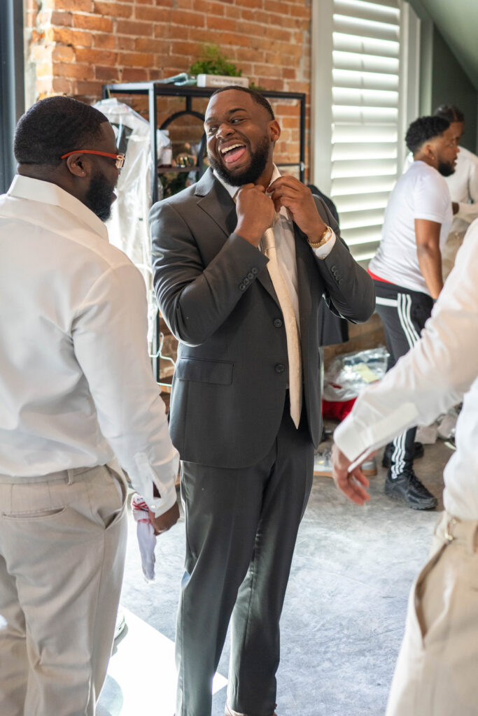 Groom laughs while getting ready with groomsmen.