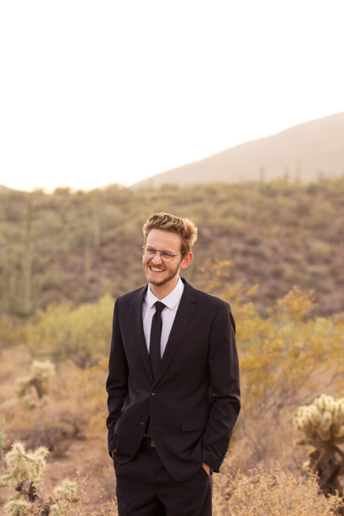 Groom laughing in the desert mountains.