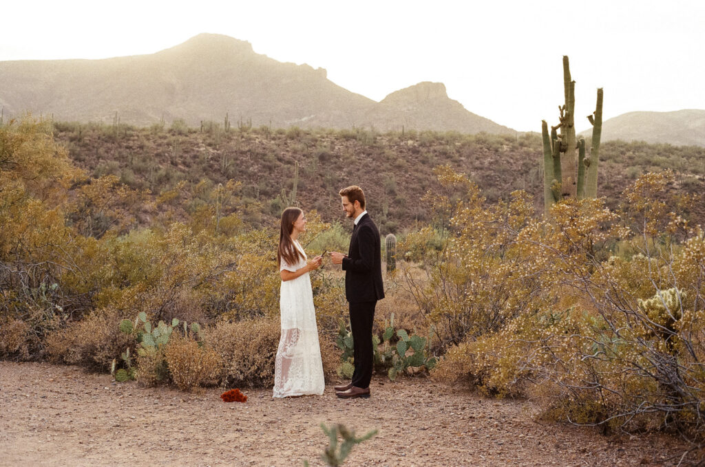 Bride and groom exchange vows during outdoor elopement in Arizona desert.
