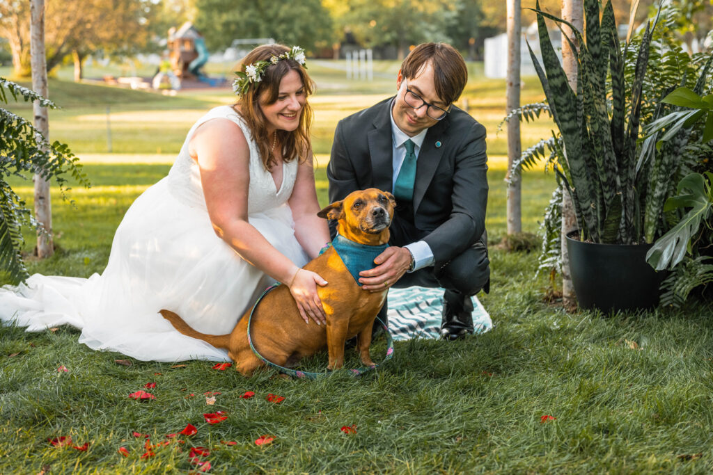 Bride and groom hug their dog after their micro wedding ceremony.