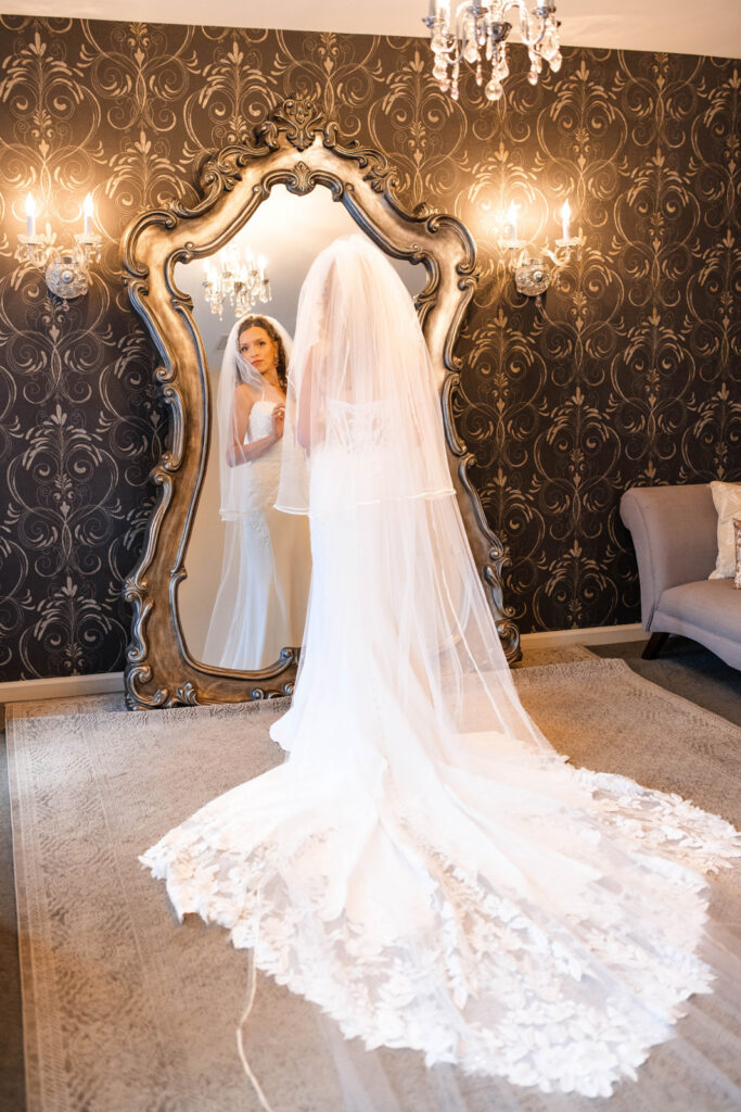 Bride getting ready in front of large mirror.