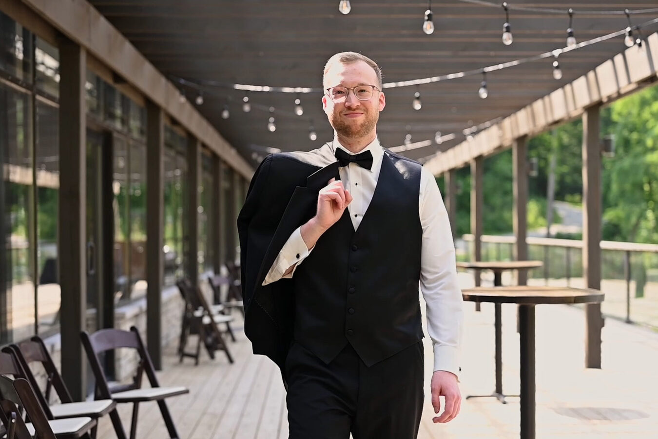 Groom smiling and walking with his jacket over his shoulder.