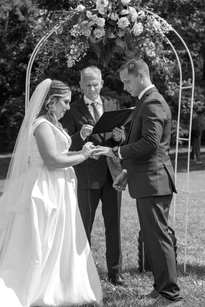 Officiant standing under arch during Indiana outdoor wedding marrying bride and groom.