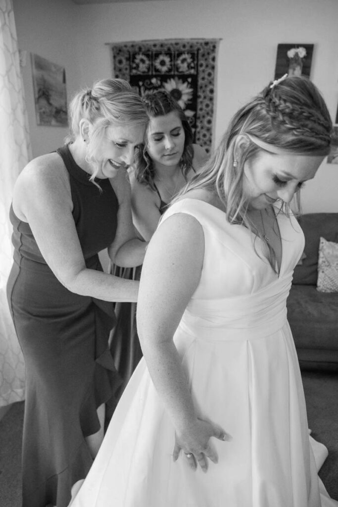 Bride's mom zips her into her wedding dress for her Indiana outdoor wedding.