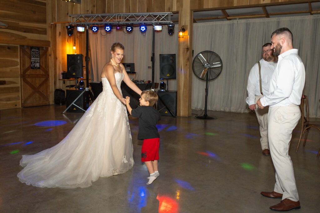 Bride and groom dance with son at wedding reception at The Barn at Timber Ridge.