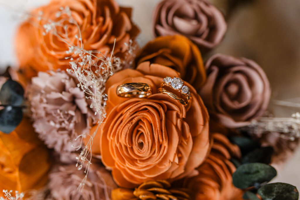 Wedding rings sitting on wooden flowers.